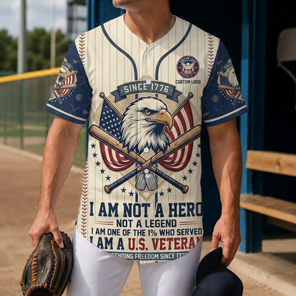 A male model wearing the custom cream US veteran patriotic baseball jersey standing inside a baseball field dugout holding a leather glove.