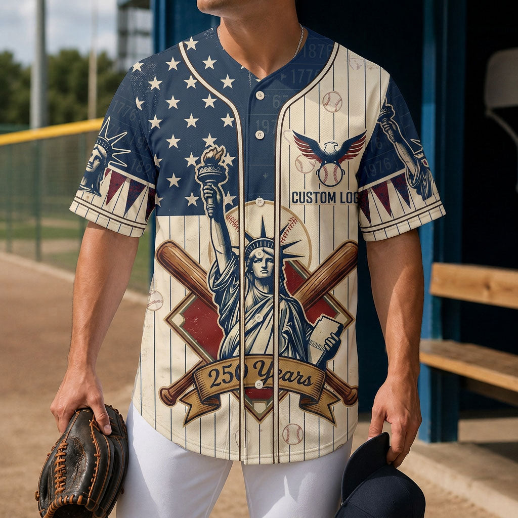 A male model wearing the custom cream Statue of Liberty USA 250th anniversary baseball jersey standing inside a baseball field dugout.
