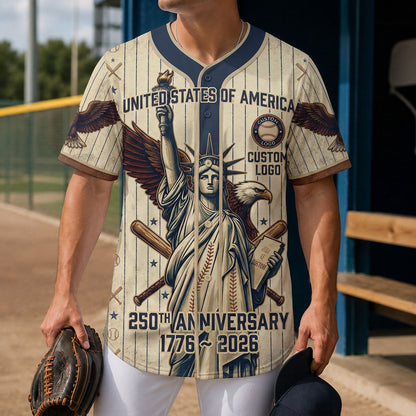 A male model wearing the custom cream Statue of Liberty USA 250th anniversary baseball jersey standing inside a baseball field dugout.