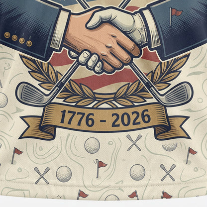 Close up shot of the patriotic golf polo showing the "We Got This" handshake graphic, crossed golf clubs, and 1776-2026 ribbon.