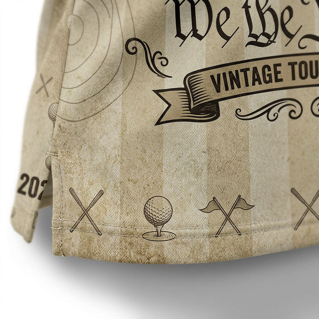 Close-up shot of the high-definition printed bald eagle crest, crossed golf clubs, and We The People script text on a premium polo shirt.